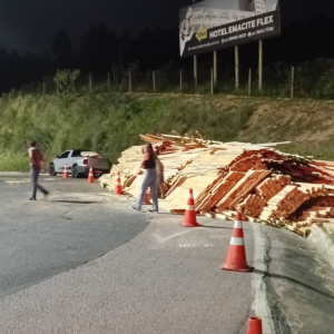 Carreta carregada com madeira tomba e deixa duas pessoas feridas