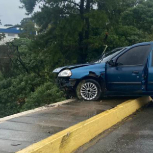 Carro rompe parapeito de viaduto e fica com roda suspensa